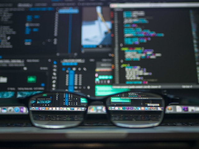 Image of glasses in front of a blurred laptop